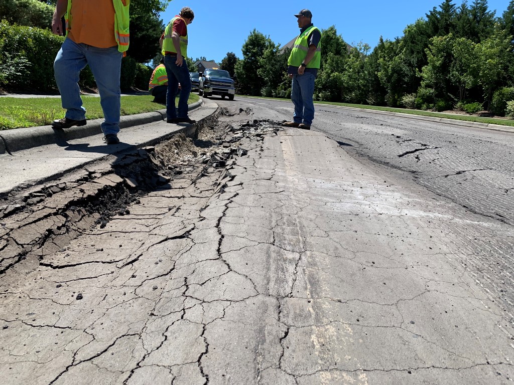 Workers standing on cracked asphault road