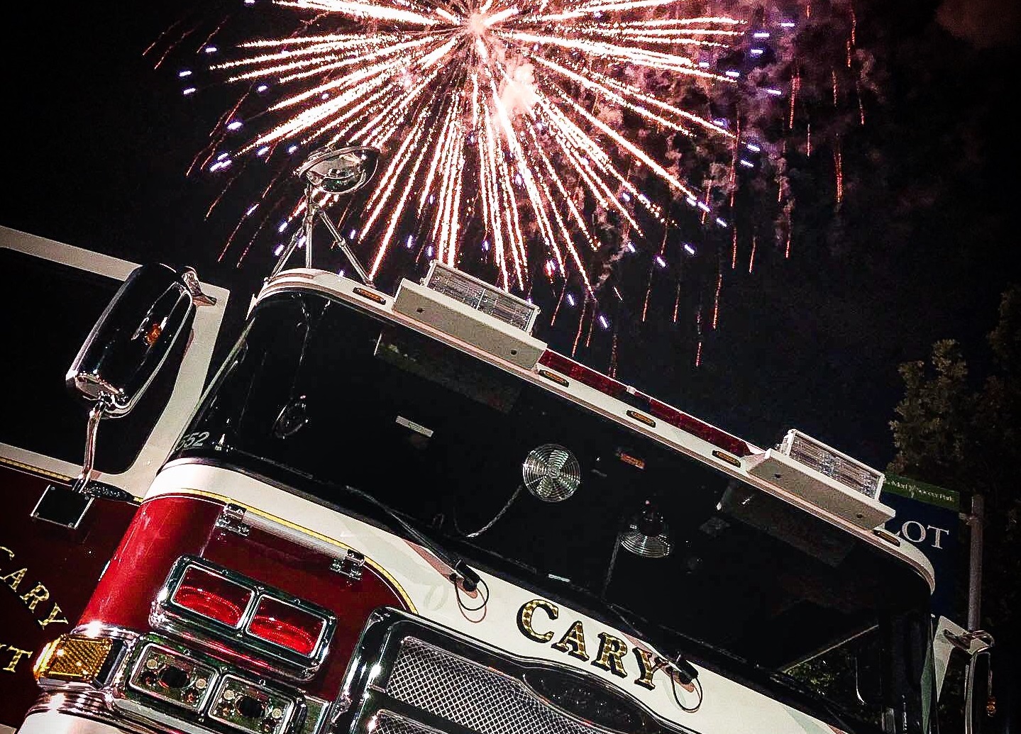 Firetruck with fireworks exploding overhead