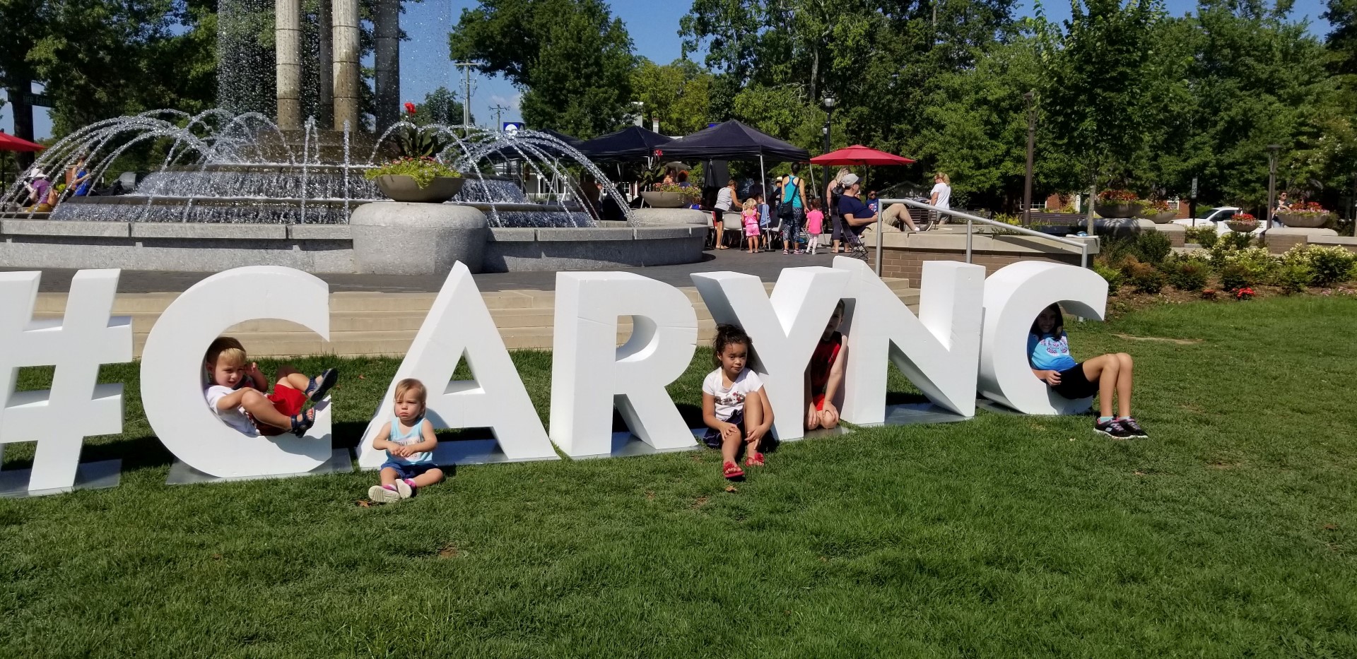 Children sitting on and around Cary, NC sign