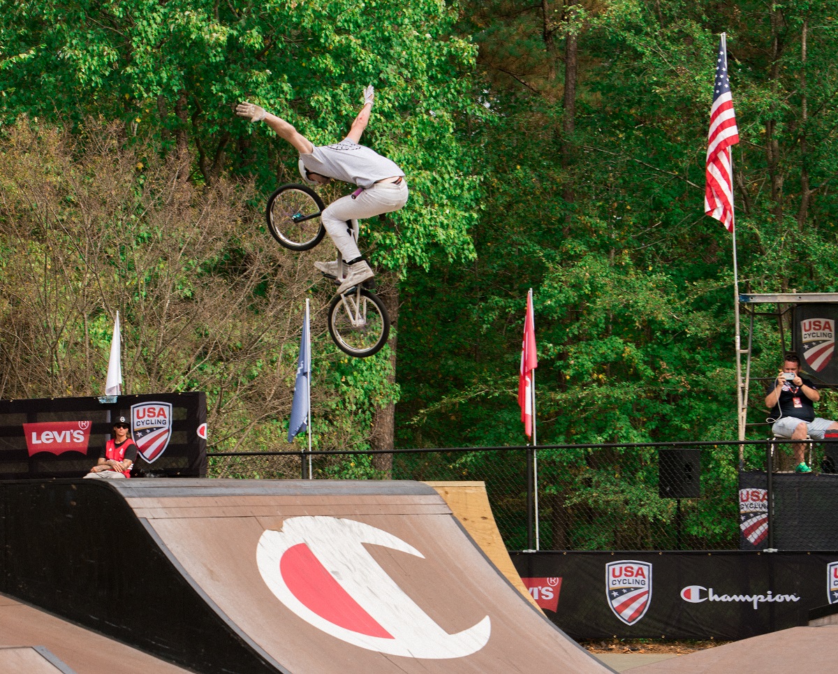 BMX biker with arms outstretched jumping from a half-pipe ramp