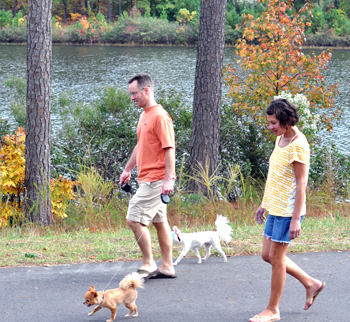 couple walking with on greenway with a dog