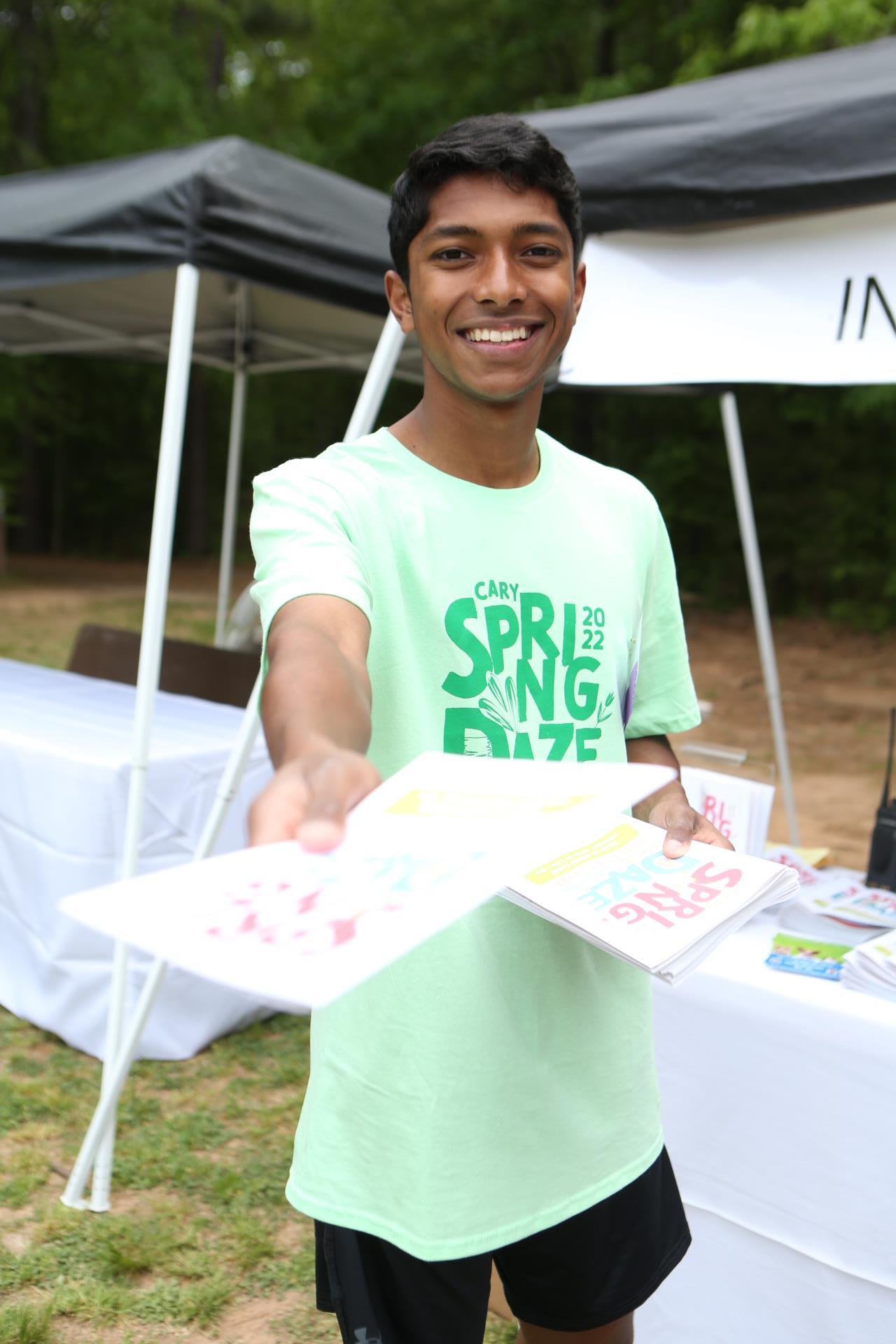 Volunteer handing out festival booklet at Spring Daze