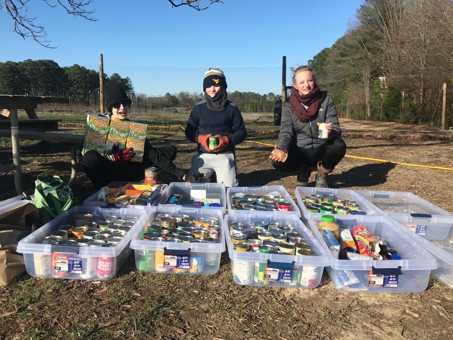 People standing behind bins of collected food items outdoors